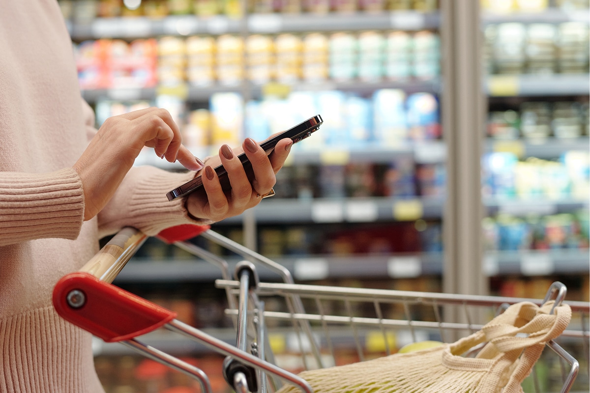 women at grocery store with her phone in hand